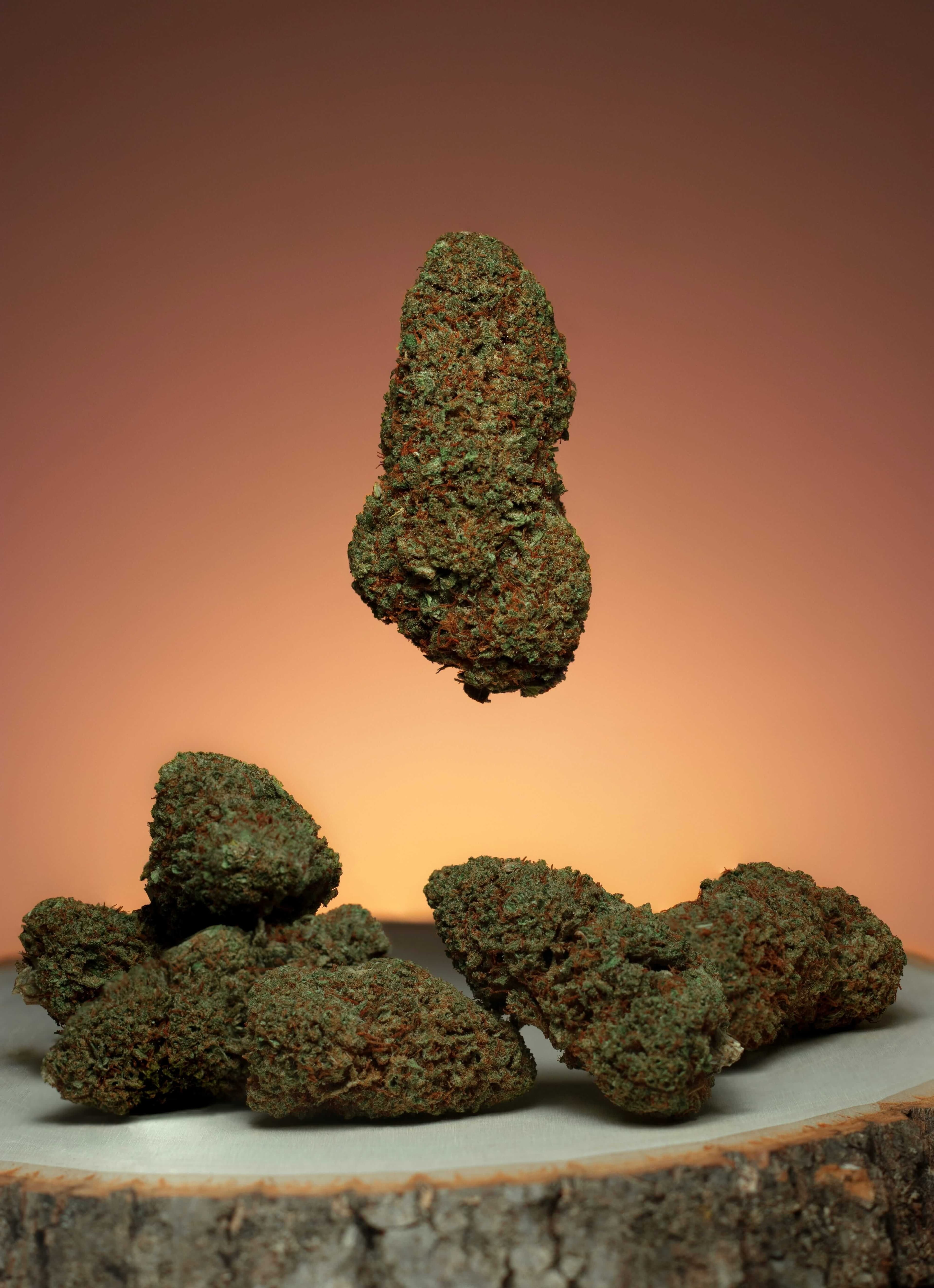Cannabis Buds with Pipe and Lighter Ready for Use Cannabis flower, a colorful glass smoking pipe, and a torch lighter arranged on a wooden table.